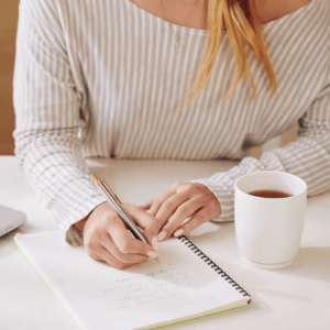 Woman writing affirmations in a notebook for morning meditation
