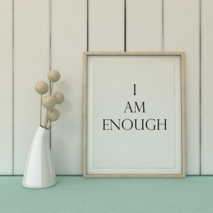 a sign on a desk that reads "I Am Enough" with a small white vase next to it