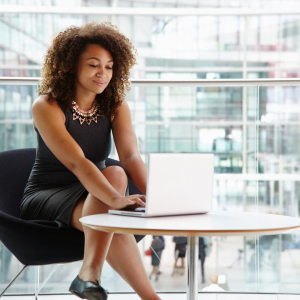 a business woman sitting at a coffee table working on a laptop