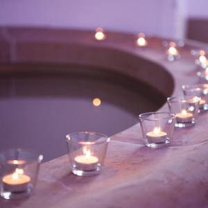 aligned tea candles lit in glass around a water fountain