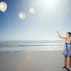 Woman on the beach releasing balloons