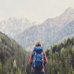 A woman backpacking looking over forested hills