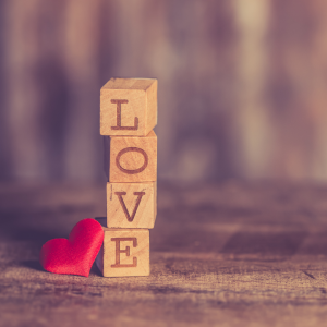 Wooden blocks lined upright spelling the word "Love" next to a small red heart