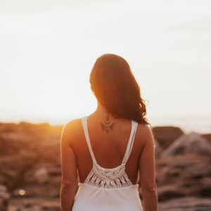 A woman looking onto a rocky beach as the sunsets