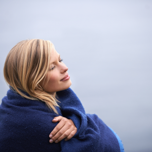 A woman wrapped in a blue blanket looking up to the sky