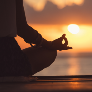 A woman sitting on a pier watching the sunset