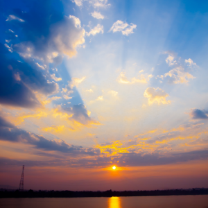 The sun rising in the blue skies over a lake