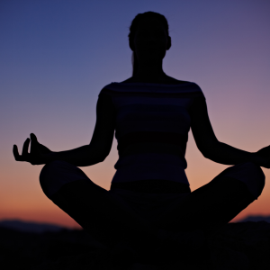 A woman holding a sitting yoga pose in the outside in the night