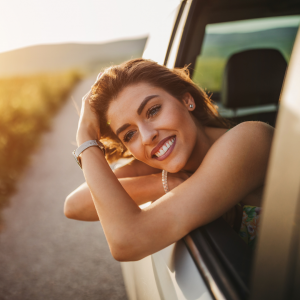 A woman in the passenger side of the car leaning out of her window smiling