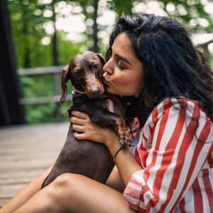 A woman outside kissing her dog in the cheek and hugging them