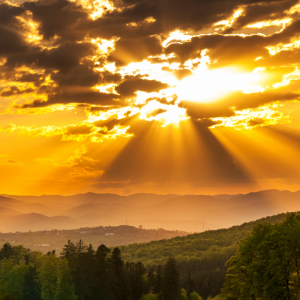 In the peak of the mountains the sun peaks through the clouds
