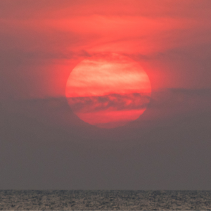 A red sun setting on the ocean