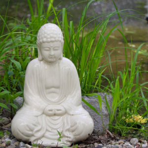 A marbleized buddha statue in a sitting posture on the grass