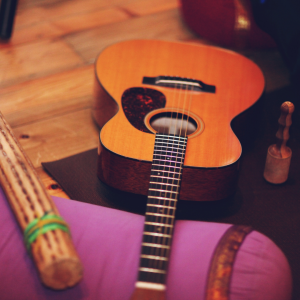 An acoustic guitar resting on a purple pillow