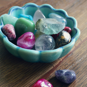 A flower-shaped bowl filled with different crystals placed on wooden table