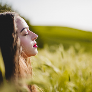 A woman with her eyes closed in deep meditation sitting on the grass