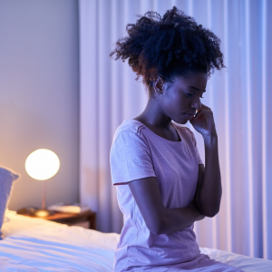 A woman sitting up on her bed overthinking