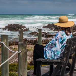 A woman sitting on a deck watching the ocean