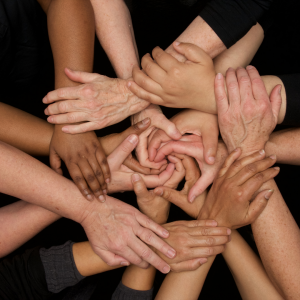 A group of hands of different ethnicities holding each other