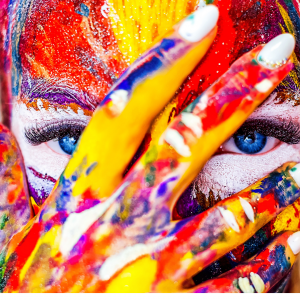 A woman's face covered in paint looking into the camera