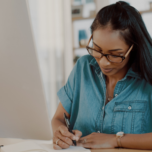 A woman sitting at her desk writing in a notebook