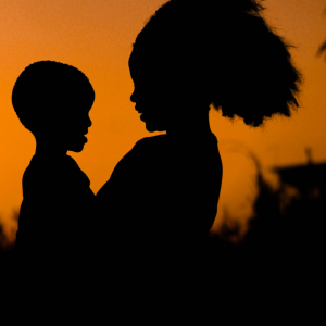 A woman holding their child and watching the sunset
