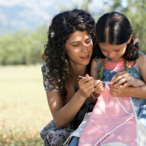 A mother showing her young daughter a flower outside