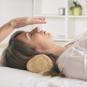 A woman laying down on a table with her eyes and a pair of hands above her