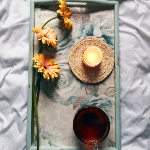 a breakfast tray with flowers a cup of tea and a candle placed on the bed