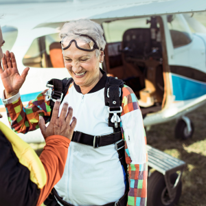 An older woman high-fiving their friend before going sky diving