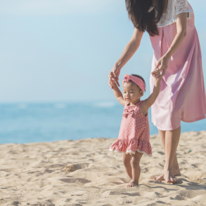 A baby girl taking her first steps on a beach