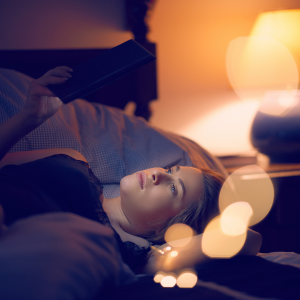 A woman relaxed in bed reading her tablet