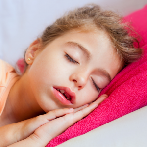 A child laying down n a pink pillow in seep sleep