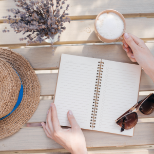 A woman sitting at a bench with a cup of and a journal