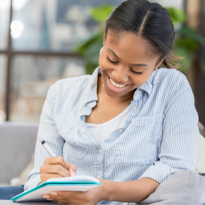 A woman happily smiling while writing in her journal