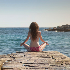 A woman sitting down at the end of the dock looking over the lake