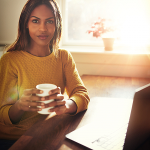 A woman enjoying a cup of coffee before writing on her laptop