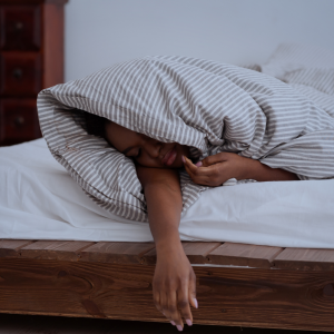 A woman wrapped in a blanket laying down in her bed