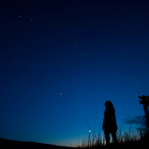 A woman outside at night watching the starlit sky