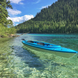 A kayak on a crystal clear lake with a mountain scene in the background