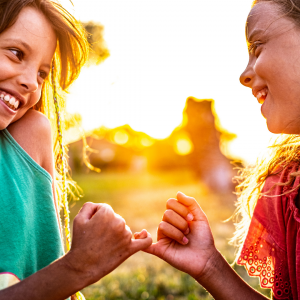 Little girls smiling and making a pinky promise with each other