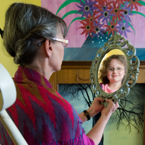 An elderly woman looking into a mirror that shows her younger self