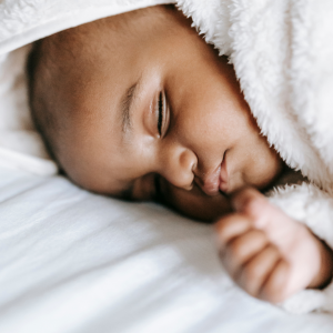 A baby sleeping on a soft sheet and wrapped around a soft blanket